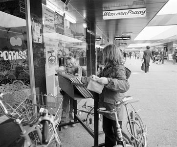 858425 Afbeelding van twee meisjes die een bak met grammofoonplaten bekijken bij de platenwinkel van Max van Praag in ...